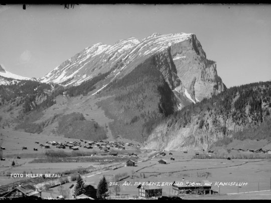 ein Schwarz-Weiß-Foto einer Stadt unterhalb eines Berges